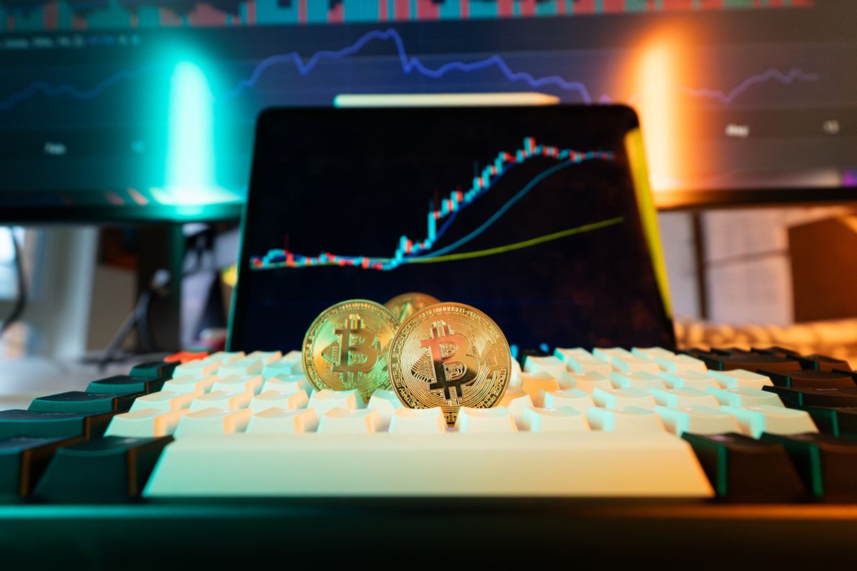 Bitcoin coin on a smartphone screen showing a price chart declining